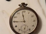 a pocket watch sitting next to a watch on a table