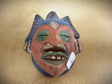 a mask on the wall with a tag on it