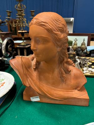 un buste de femme assise sur une table à côté d'une machine à coudre