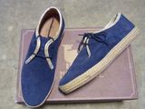 une paire de chaussures en daim bleu posée sur une boîte, posée à son tour sur le sol