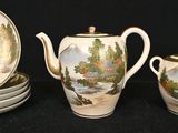 a tea pot and four plates with a painting on it