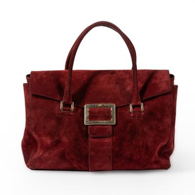 a red sued handbag with a metal buckle on the front