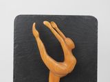 an image of a wooden sculpture of a woman on a black surface