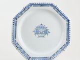 blue and white plate with a basket of flowers on it