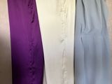trois paires de pantalons suspendues à un portant devant un mur