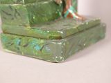 a small statue of a woman sitting on a green box