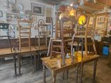 tables and chairs in a room with wooden floors and a clock on the wall
