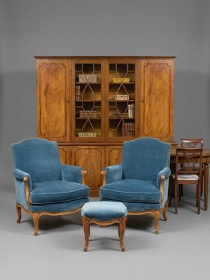 deux chaises bleues et une table dans une pièce où se trouve une bibliothèque