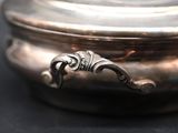 a silver plate with a lid on a black table