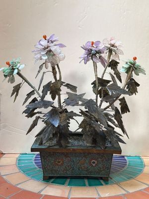 une jardinière en métal remplie de fleurs, posée sur un sol carrelé