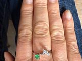 a woman ' s hand with a diamond and emerald ring
