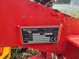 un gros plan d'un tracteur rouge sur lequel est accrochée une pancarte