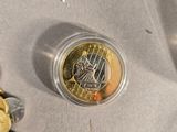 coins and a coin sitting on a table next to a cup
