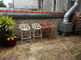 trois chaises posées sur une terrasse en bois, à côté d'une plante en pot