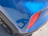 a close up of a blue car with a red tail light