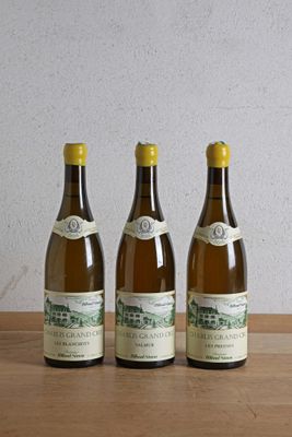 trois bouteilles de vin posées sur une table en bois à côté d'une bouteille de vin