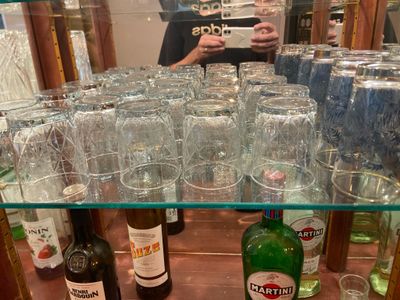 many glasses and bottles of alcohol on a shelf