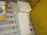 a pile of cement blocks on a pallet next to a yellow bin