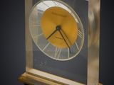 une horloge en verre avec un cadran jaune sur fond noir