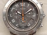 an orange strap around a watch face on a white surface