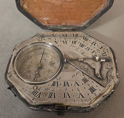 a silver clock inside of a wooden box on a table