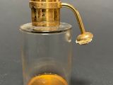 yellow liquid in a glass jar with a gold handle on a gray surface