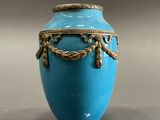 a blue vase with a gold decoration on it