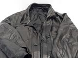 une veste en cuir noir posée sur une table blanche