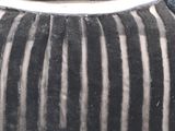 a black and white striped vase with a black hat on top