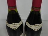 two bottles of red wine sitting next to each other on a counter