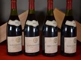 four bottles of wine are lined up on a red table