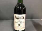 une bouteille de vin rouge posée sur une table à côté d'un verre de vin