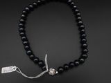 un gros plan sur un collier de perles noires muni d'un fermoir en argent
