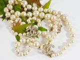 un collier de perles et une broche posés sur une table
