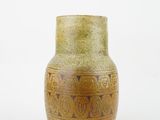 yellow and brown vase sitting on a white surface with a white background