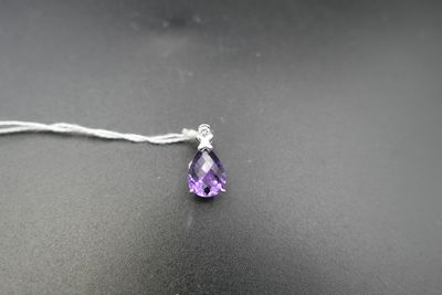 un gros plan d'un collier orné d'une pierre violette