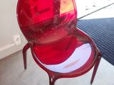 une chaise en plastique rouge posée devant une porte vitrée