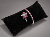 a black pillow with pink and white crystals on it