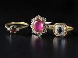 three gold rings with diamonds and a ruby stone