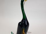 a glass duck that is sitting on a white surface