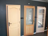 three wooden doors in a room with a black wall