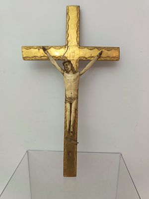 a gold cross on a glass table with a white wall in the background