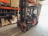 un chariot élévateur dans un entrepôt, avec des cartons sur les rayonnages