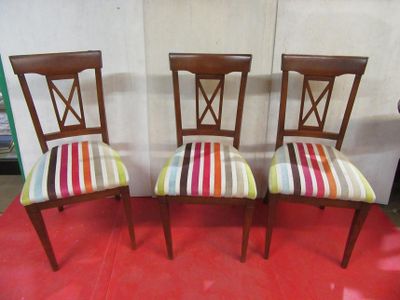 three wooden chairs with colorful striped upholstered seats on a red carpet