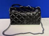 a black quilted purse on a white table with a blue background