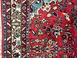 un tapis persan ancien à fond rouge et bordure bleue
