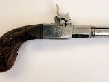 un vieux pistolet avec une poignée en bois sur une surface blanche