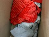 a cardboard box filled with clothes and a red blanket