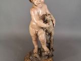 an antique statue of a child holding a bird on top of a table