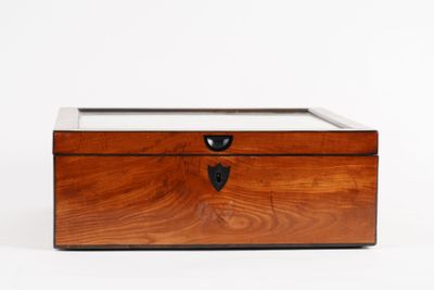 une petite boîte en bois avec un couvercle en verre, posée sur une surface blanche